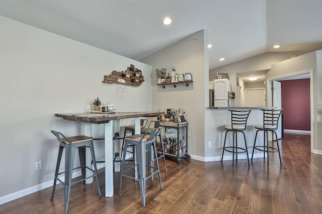 dining space featuring dark wood-type flooring, baseboards, a dry bar, vaulted ceiling, and recessed lighting