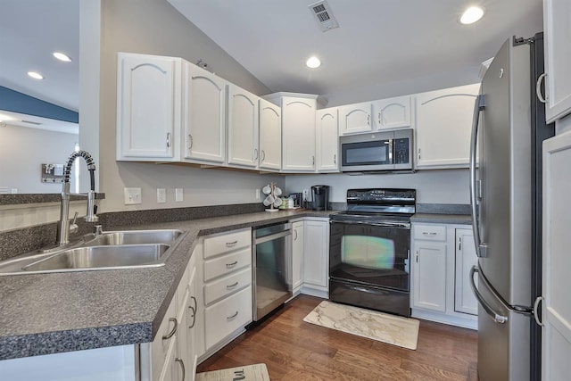 kitchen with visible vents, a sink, dark countertops, dark wood-style floors, and stainless steel appliances