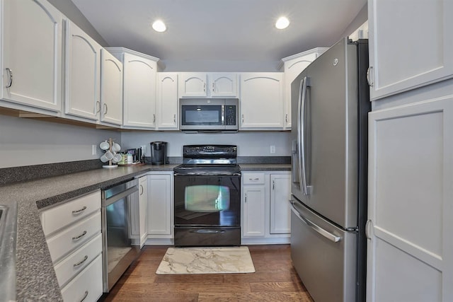 kitchen with dark countertops, dark wood finished floors, appliances with stainless steel finishes, and white cabinets