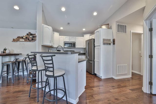 kitchen featuring visible vents, a breakfast bar area, a peninsula, and stainless steel appliances