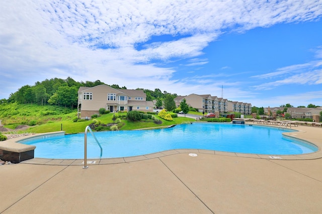 community pool with a patio, a yard, and a residential view