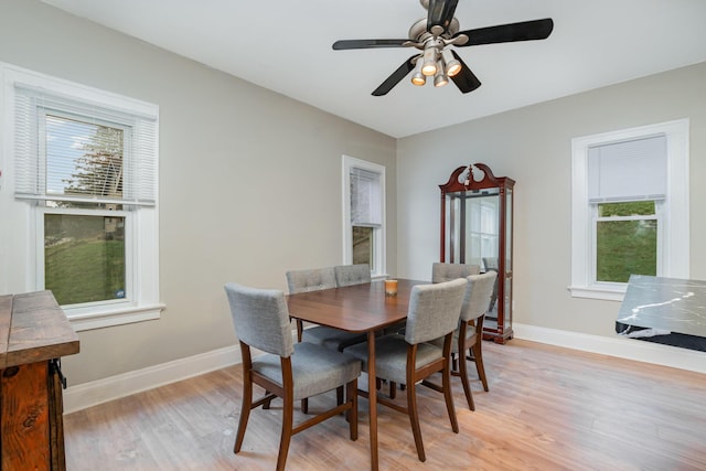 dining space with a ceiling fan, light wood finished floors, and baseboards