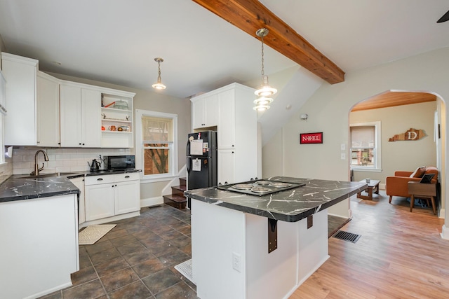 kitchen with arched walkways, decorative backsplash, dark countertops, beamed ceiling, and black appliances