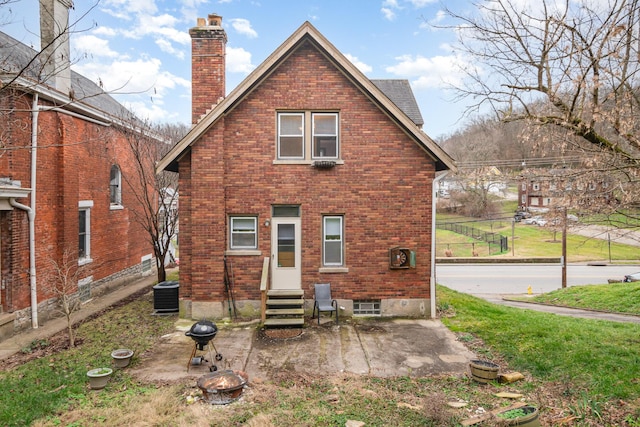 back of property featuring brick siding, a chimney, entry steps, central AC, and a fire pit