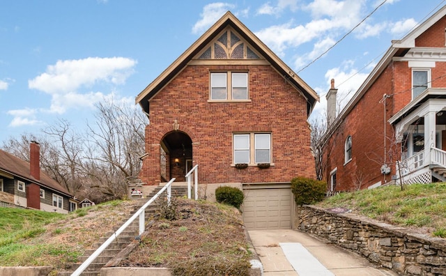 tudor home with brick siding, driveway, and an attached garage