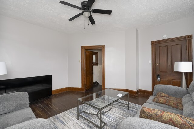 living room with baseboards, a textured ceiling, and wood finished floors