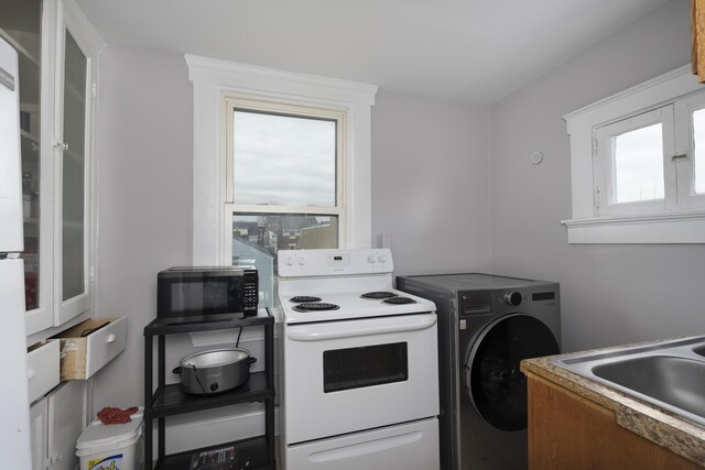 kitchen with glass insert cabinets, washer / dryer, electric stove, and a sink