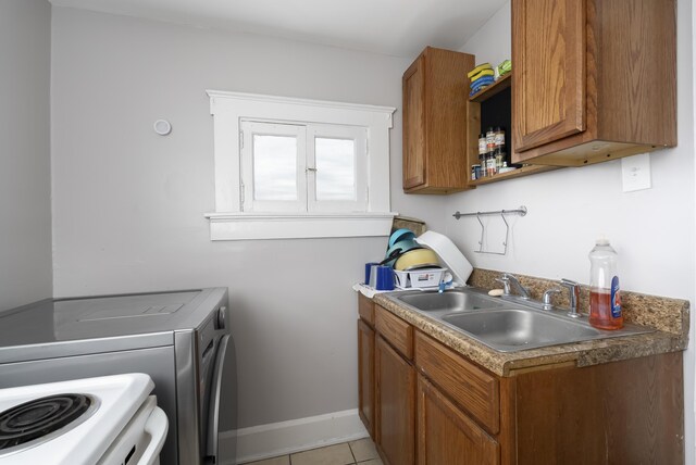 washroom featuring a sink, light tile patterned floors, baseboards, laundry area, and washing machine and clothes dryer