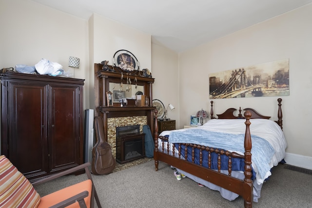 bedroom with a glass covered fireplace, baseboards, and carpet floors