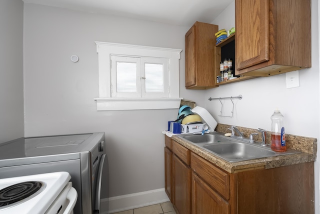 laundry room featuring washing machine and clothes dryer, baseboards, laundry area, light tile patterned flooring, and a sink