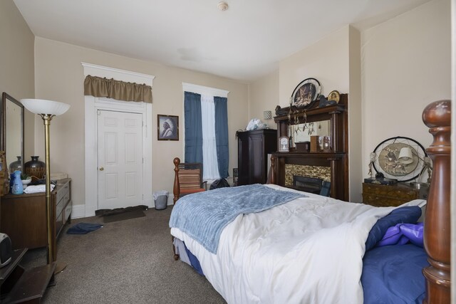 bedroom featuring dark colored carpet, baseboards, and a fireplace