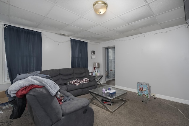 living area with a drop ceiling, baseboards, and carpet