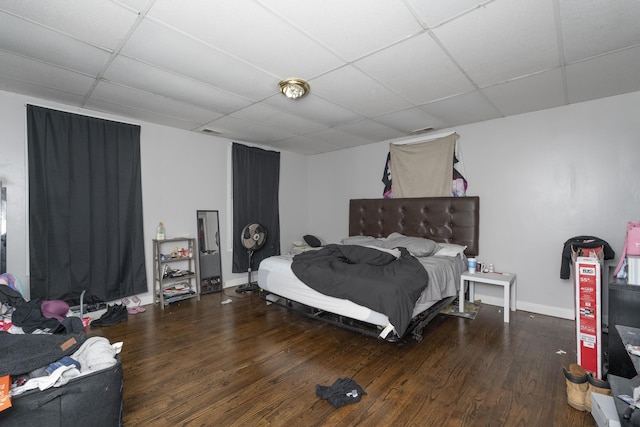 bedroom with a drop ceiling, baseboards, visible vents, and wood finished floors