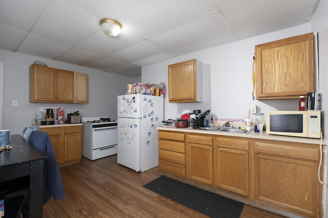 kitchen featuring a paneled ceiling, white appliances, dark wood-type flooring, and light countertops