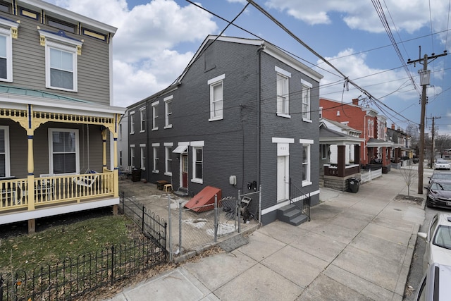 view of home's exterior featuring entry steps, a porch, fence, and brick siding