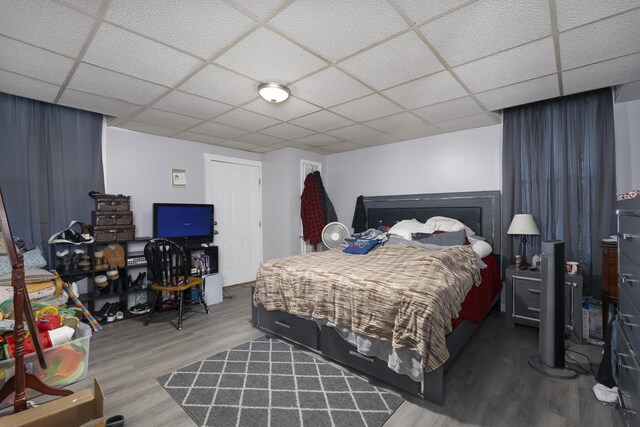 bedroom with a drop ceiling and wood finished floors