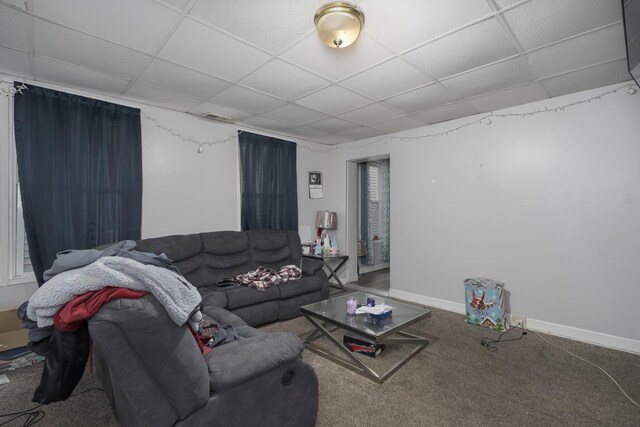 living room featuring baseboards, a paneled ceiling, and carpet