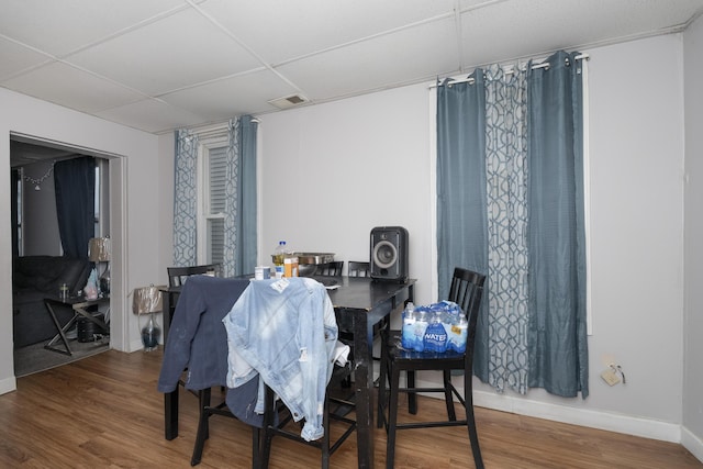 dining space featuring wood finished floors, a paneled ceiling, visible vents, and baseboards