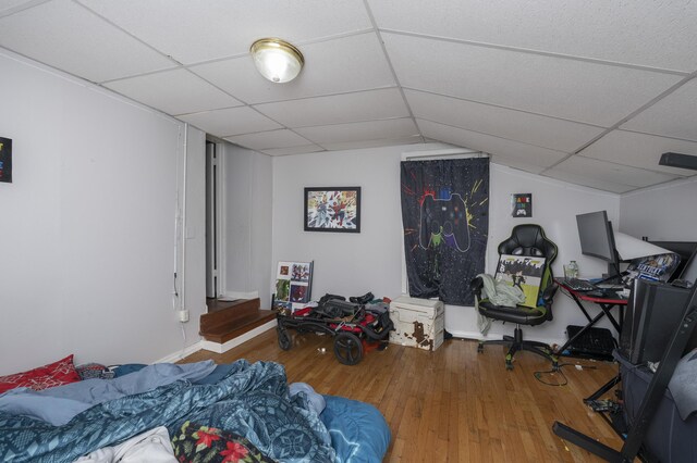 bedroom with a drop ceiling and wood finished floors