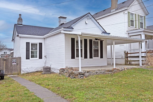 view of property exterior with central AC unit, fence, a yard, a chimney, and a patio area