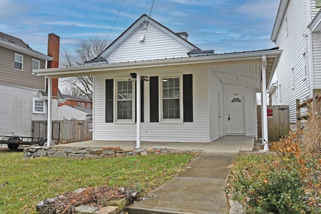 bungalow with fence, metal roof, a ceiling fan, and a front yard