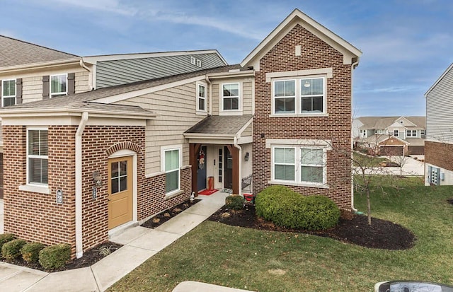 view of front of home featuring brick siding, a front lawn, and a shingled roof