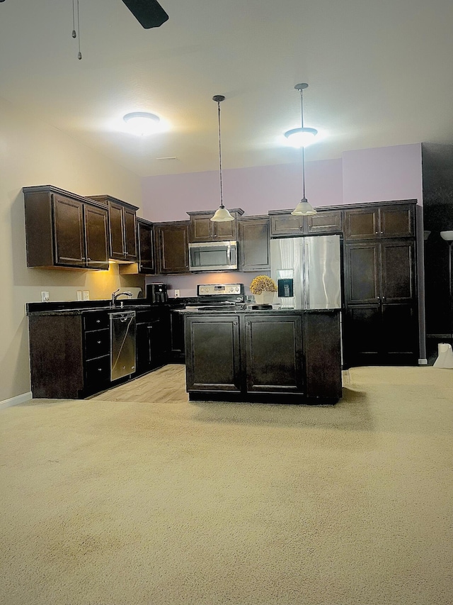 kitchen with stainless steel appliances, dark brown cabinets, dark countertops, and pendant lighting