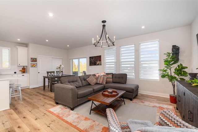 living area featuring light wood finished floors, baseboards, an inviting chandelier, and recessed lighting