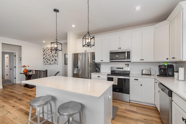 kitchen featuring light wood finished floors, tasteful backsplash, appliances with stainless steel finishes, and a breakfast bar