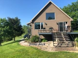 back of property featuring stairway, a deck, and a yard