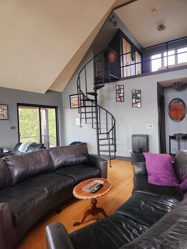 living area with stairs, high vaulted ceiling, and wood finished floors