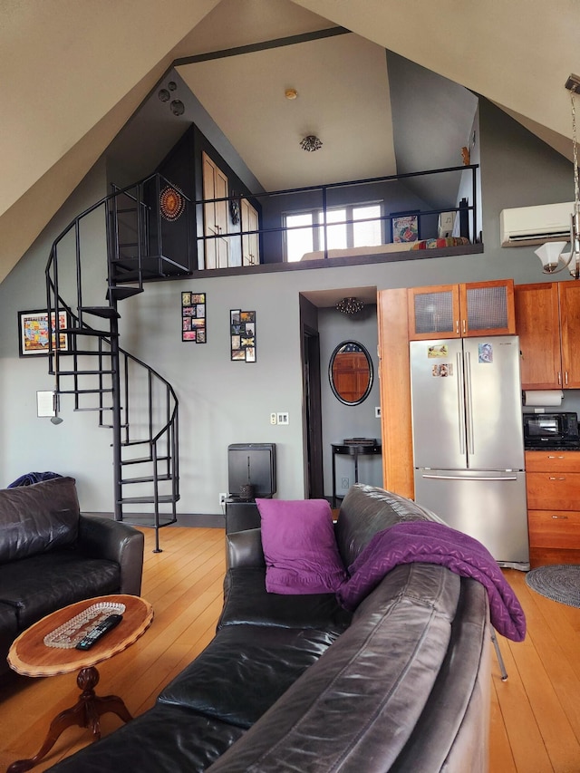 living area featuring light wood-style flooring, stairs, vaulted ceiling, and a wall mounted air conditioner