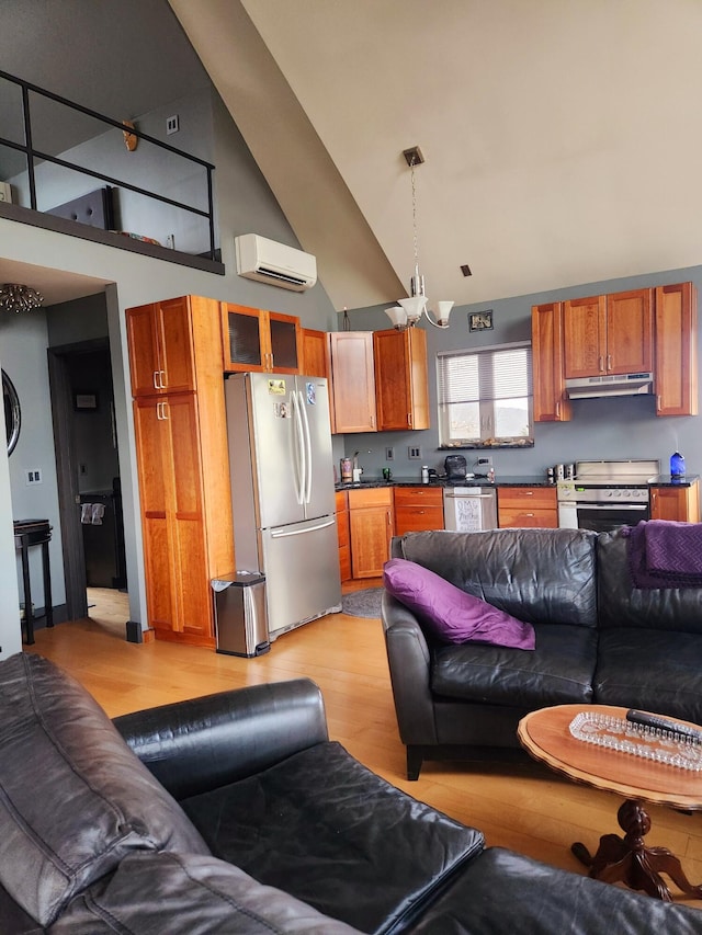 living area featuring high vaulted ceiling, an AC wall unit, light wood-style flooring, and an inviting chandelier