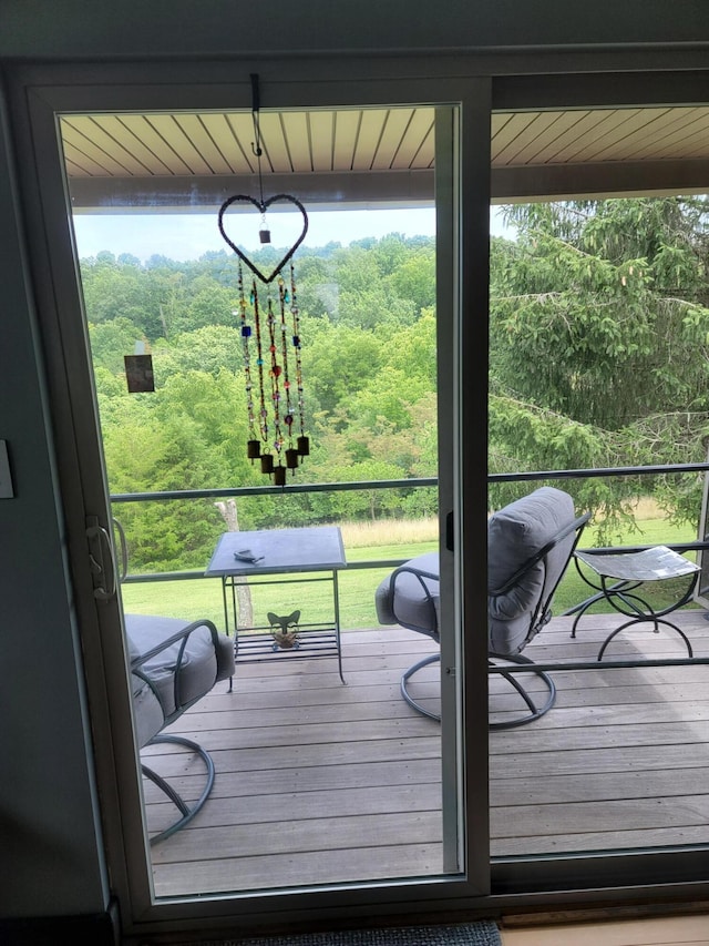 doorway featuring a healthy amount of sunlight and a wooded view