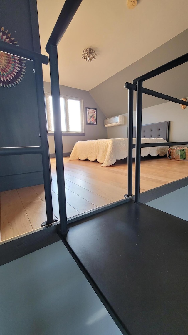 unfurnished bedroom with a wall unit AC and vaulted ceiling