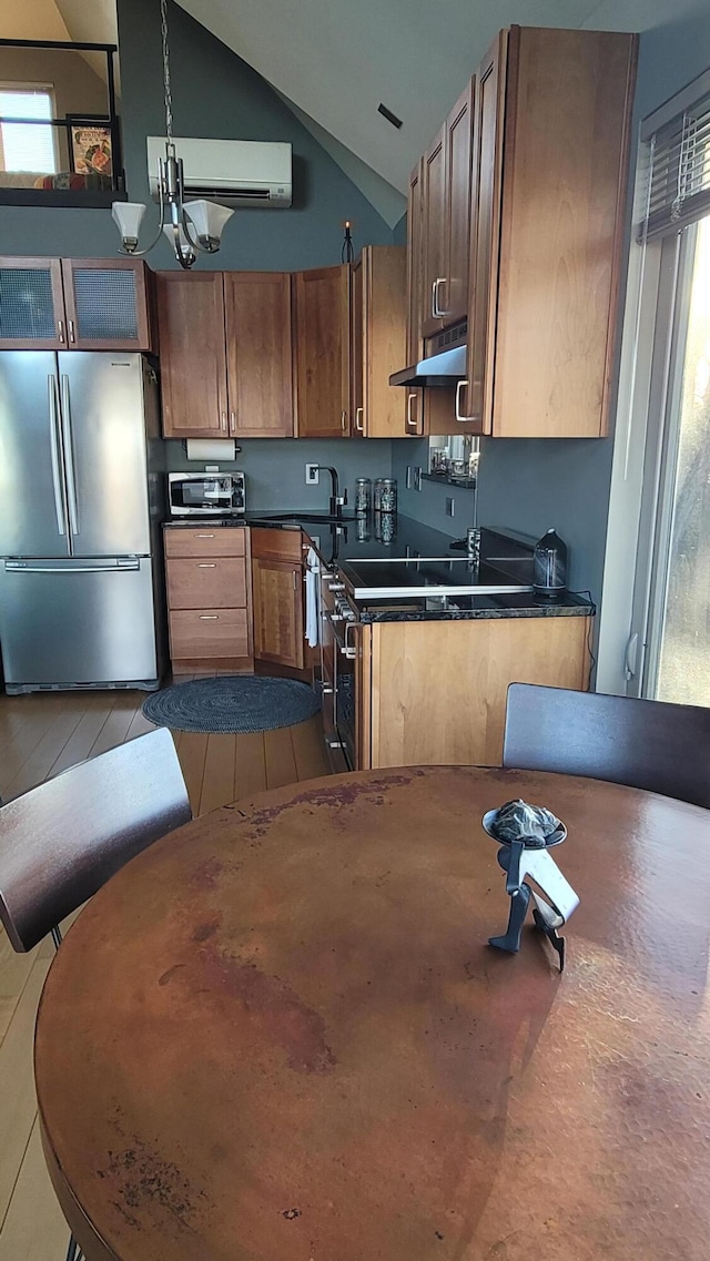 kitchen featuring dark countertops, lofted ceiling, freestanding refrigerator, under cabinet range hood, and a sink