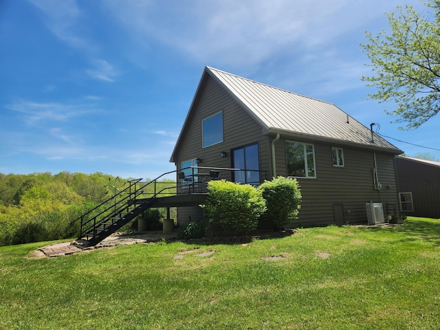 view of side of property featuring cooling unit, a lawn, stairs, and metal roof