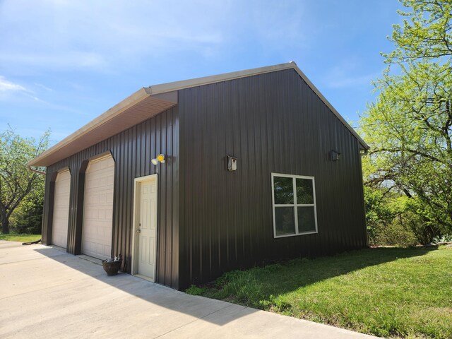 view of property exterior with a detached garage, an outdoor structure, and a lawn