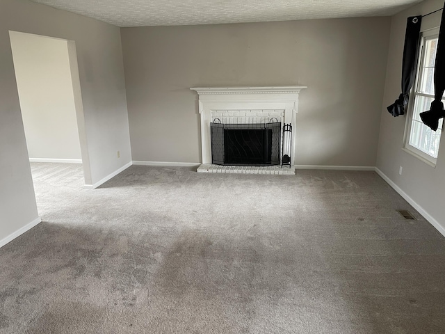 unfurnished living room featuring baseboards, a fireplace, visible vents, and a textured ceiling