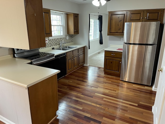 kitchen with hardwood / wood-style flooring, a sink, light countertops, appliances with stainless steel finishes, and backsplash