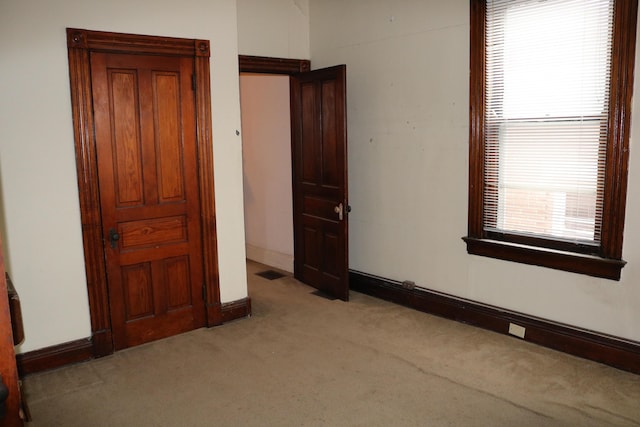 unfurnished bedroom featuring light colored carpet, visible vents, and baseboards