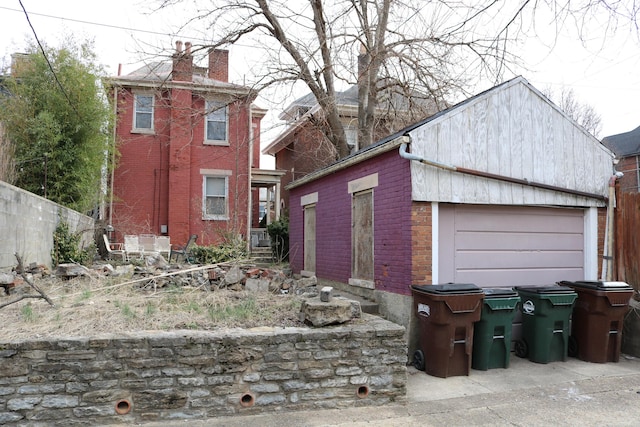 exterior space featuring an outbuilding, brick siding, a chimney, fence, and a garage