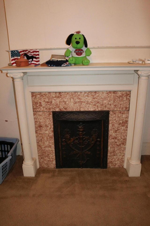 details featuring carpet flooring, decorative columns, and a tiled fireplace