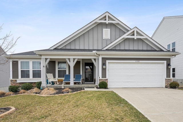 craftsman house featuring a front yard, driveway, a porch, stone siding, and board and batten siding