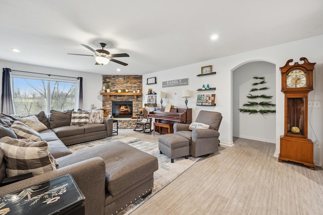 living area featuring recessed lighting, arched walkways, a fireplace, baseboards, and ceiling fan