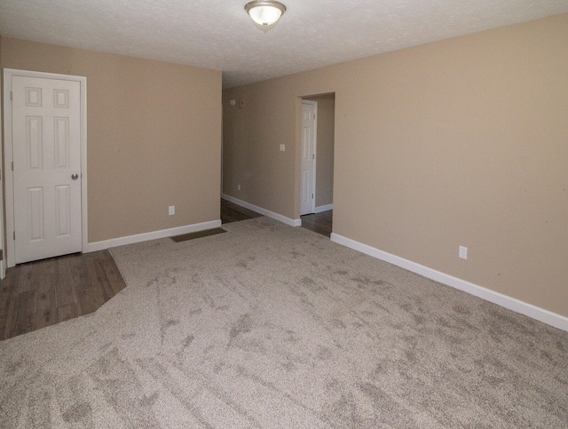 spare room with carpet, baseboards, and a textured ceiling