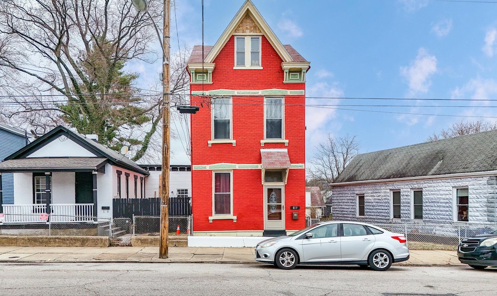 view of front of house featuring a fenced front yard, brick siding, and covered porch