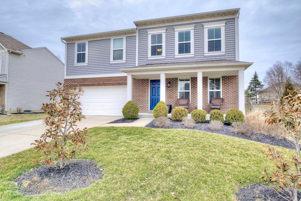 view of front of home with a garage, brick siding, concrete driveway, covered porch, and a front yard