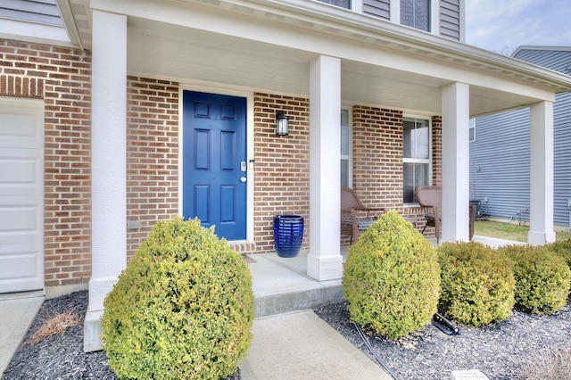 property entrance featuring a porch, brick siding, and a garage