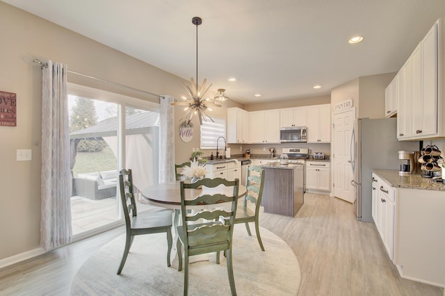 dining area featuring light wood-type flooring, an inviting chandelier, baseboards, and recessed lighting